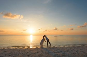 man and woman standing on shore kissing